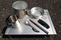 調理用具一式。コッヘルは鍋代わりの深いものと、皿代わりの浅いものを用意。コップはコーヒーやスープを飲むときに使用。箸とスプーンは不可欠。ナイフがあると調理の幅が広がる